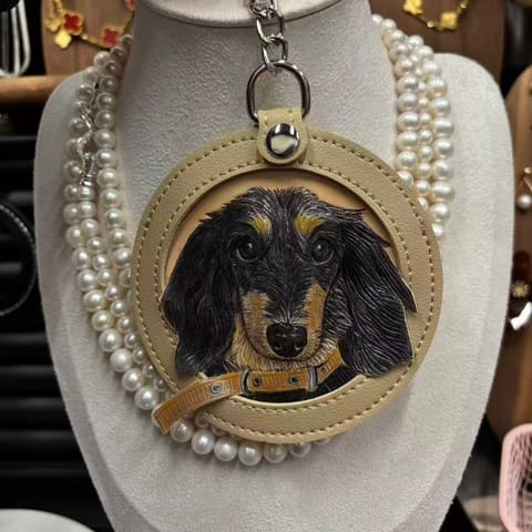 A black-and-tan dachshund carved into a cream leather medallion