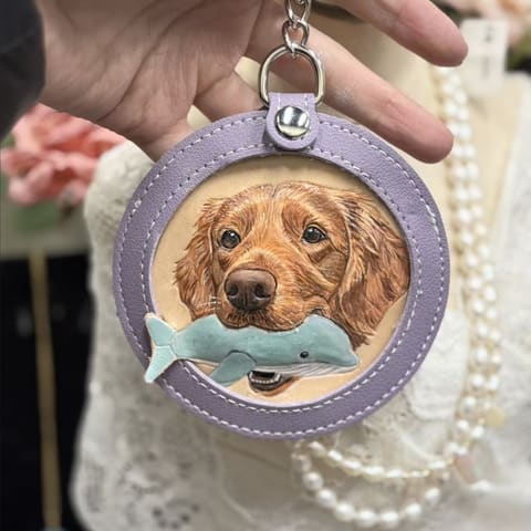 A golden retriever with a dolphin toy, carved into a lavender leather medallion